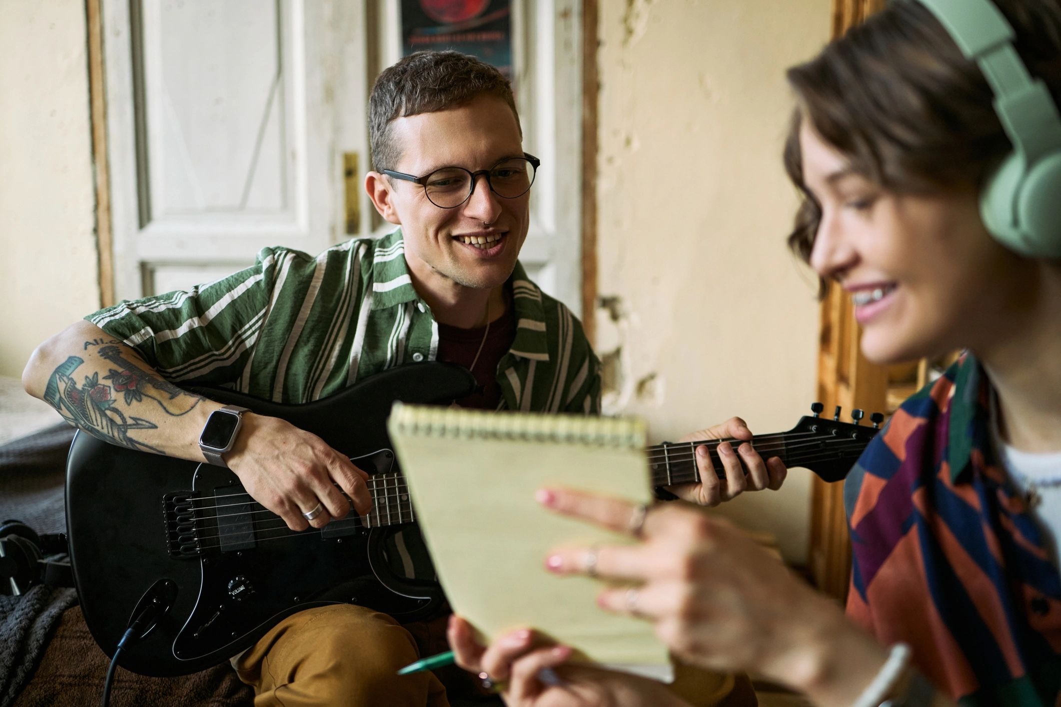 Adult woman taking notes while man plays guitar during a music lesson