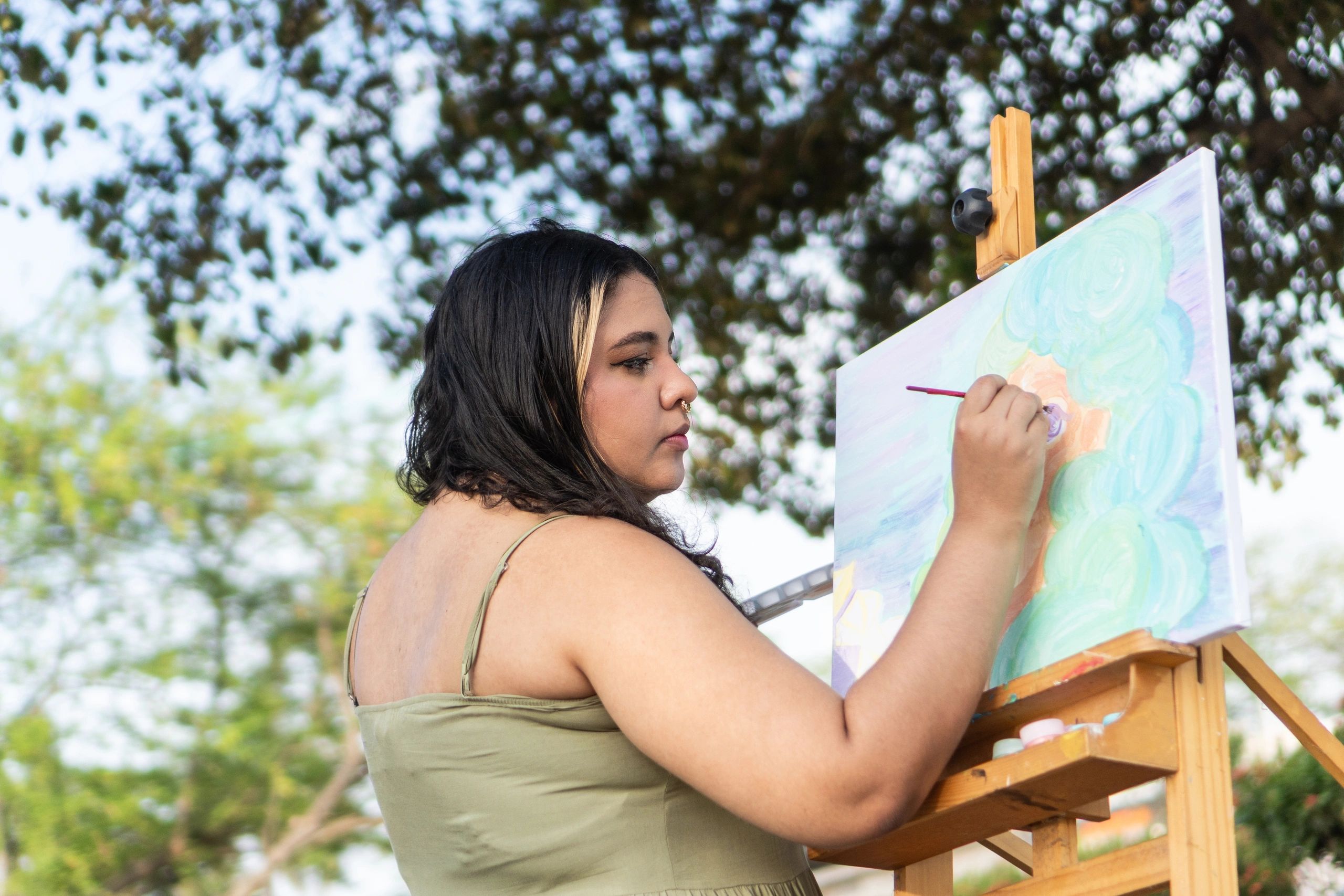 Young woman painting outdoors on an easel in park